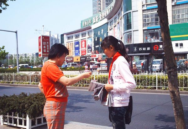 志愿者向过路行人义卖报纸